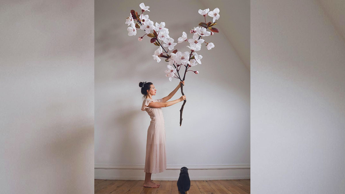 donna con grande ramo pieno di fiori e un gatto che la guarda